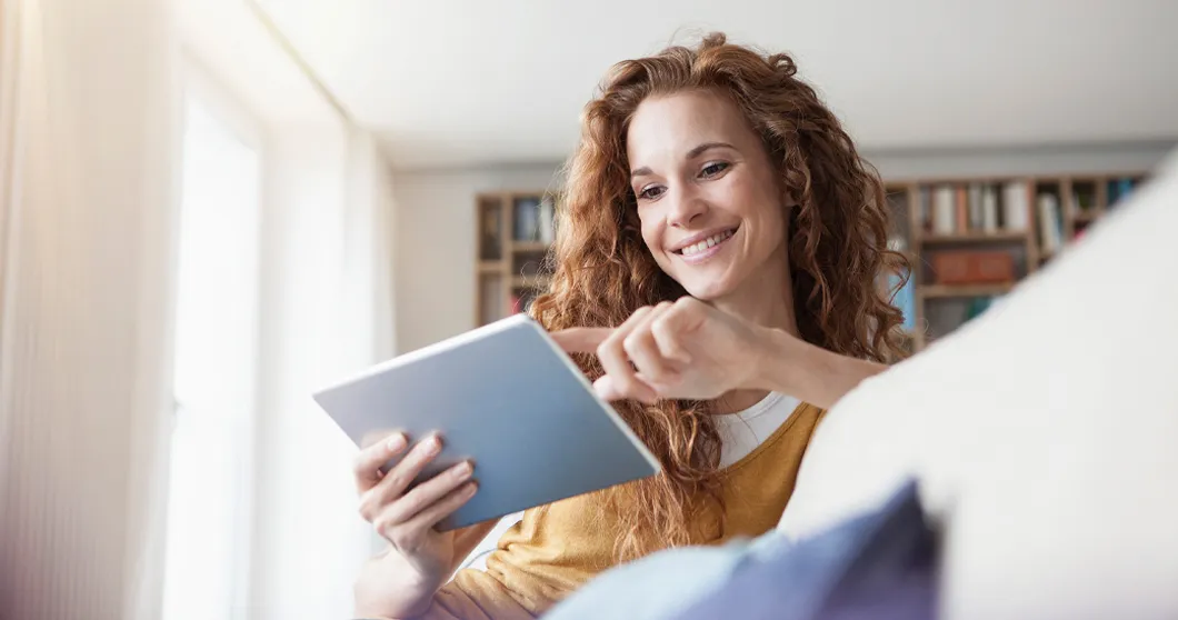 Jonge glimlachende vrouw met tablet